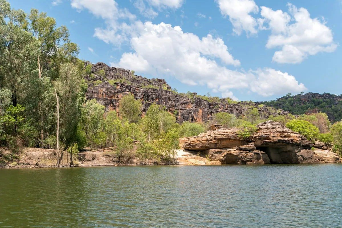 Rust-coloured rock formations beside wetlands in the Top End escarpment country of Kakadu