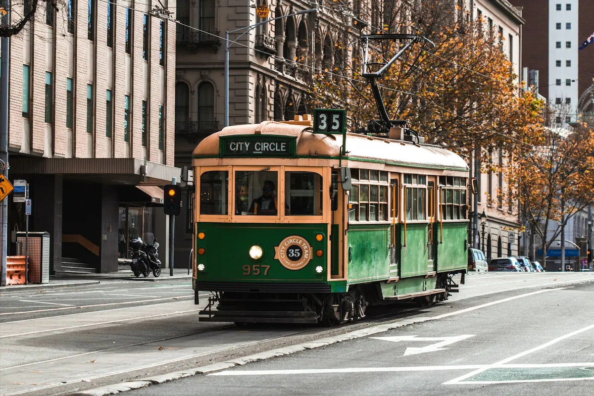 A classic green and yellow Melbourne tram on the city street