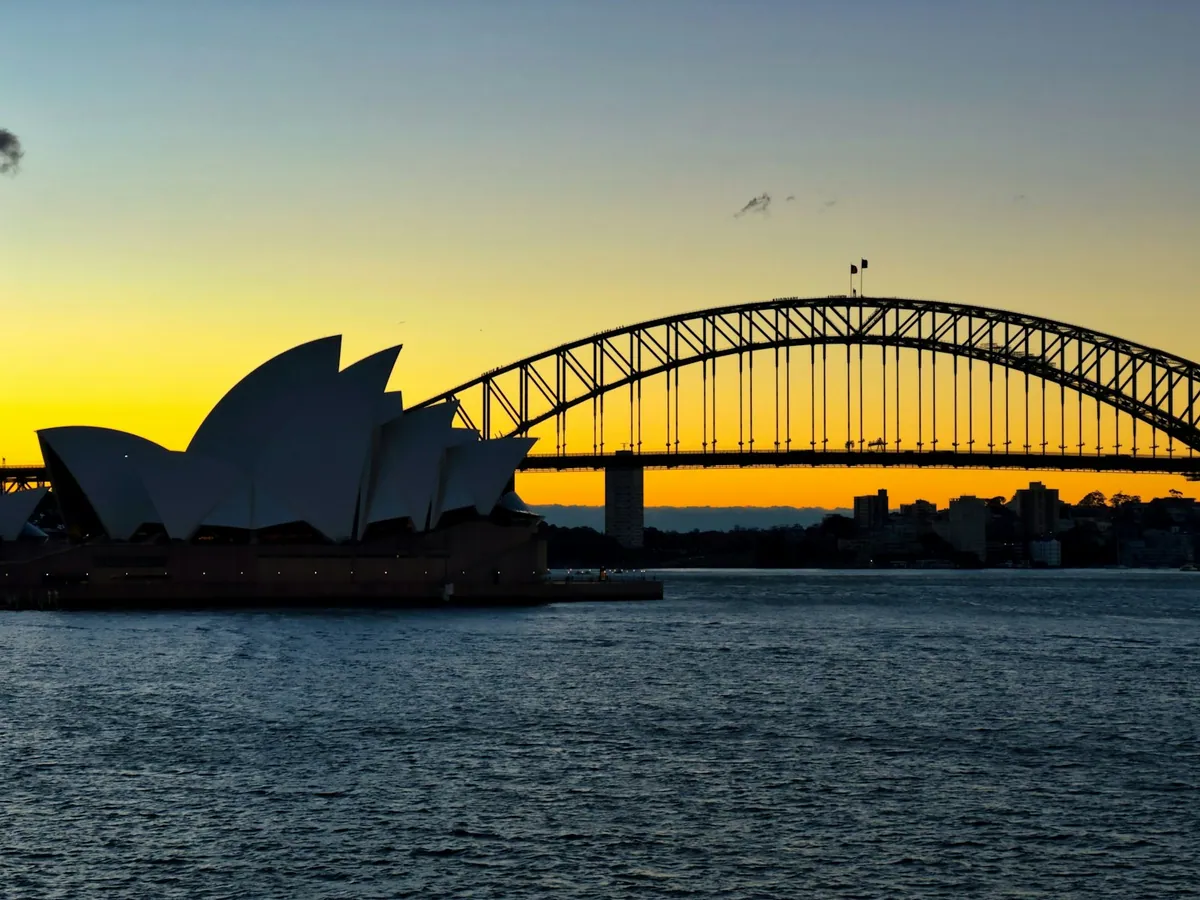 Sydney Opera House and Harbour Bridge silhouetted at sunset