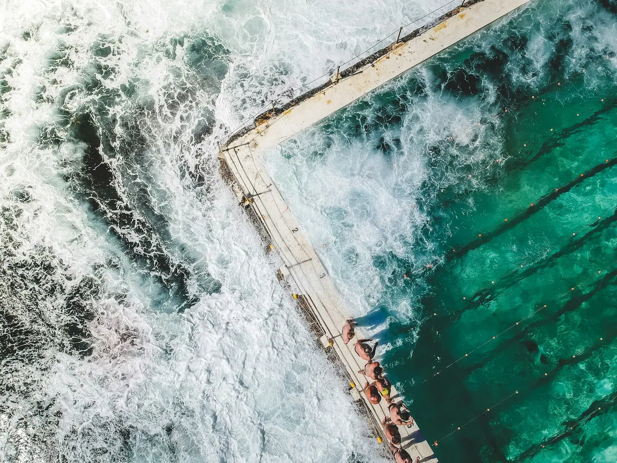 Bondi Beach crescent of sand with surf and ocean baths in the foreground