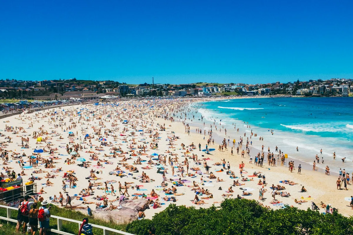 Sunbathers and swimmers on Bondi Beach on a bright summer day