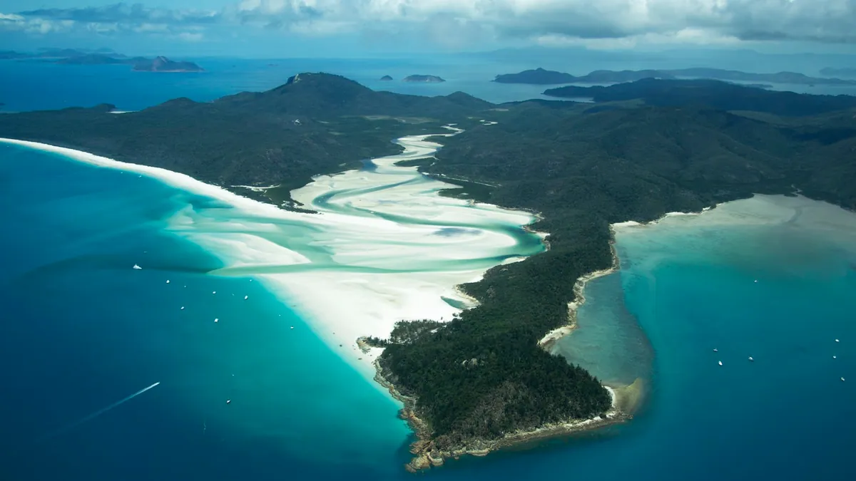 Aerial view of a Whitsunday island ringed by reef in the Coral Sea