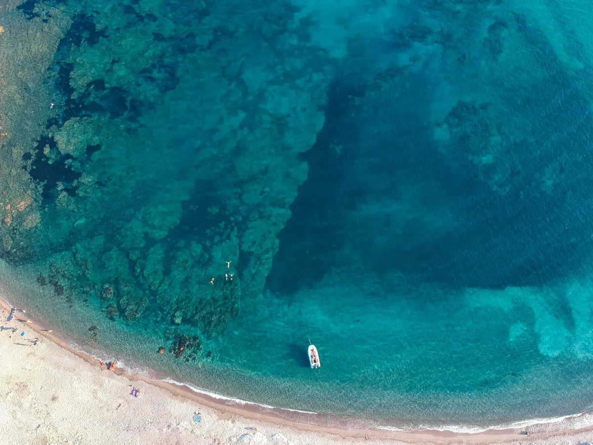 Aerial drone view of a boat in turquoise water near Bonifacio, Corsica
