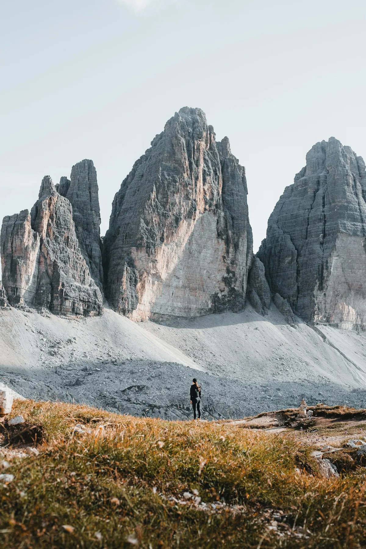 Hiker beside the snowy Tre Cime peaks in the Dolomites